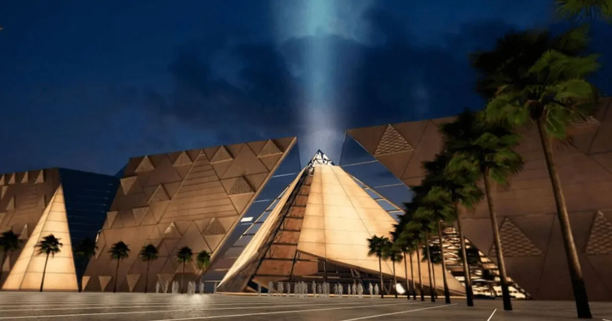 The Grand Egyptian Museum's translucent stone façade at dusk with the Giza pyramids rising behind it